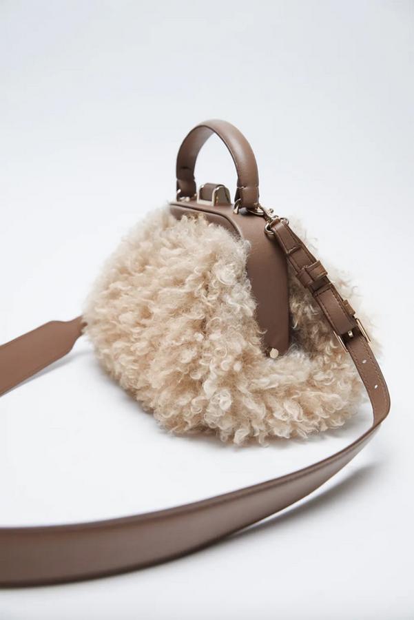 Con cuerpo en borreguillo y en color beige, esta bandolera de Zara viene con asa de mano rígida, asa de hombro ajustable y extraíble y cierre mediante imán. Tiene un precio de 35,95 euros.