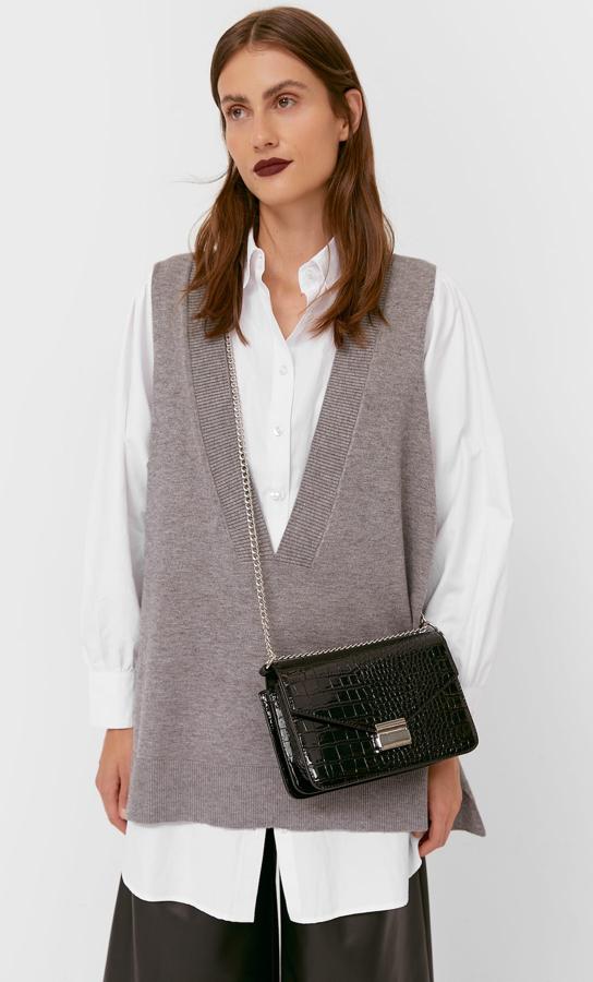 Con forma de sobre, asa de cadena y efecto coco acharolado, este bolso negro con cierre metálico es de Stardivarius (19,99 euros).