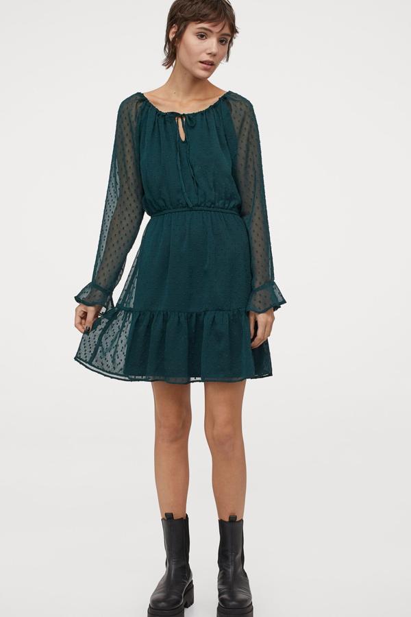 Este vestido corto en gasa plumeti de color verde oscuro cuenta con amplio escote y abertura con cordón de ajuste. Con volante en los puños y en el bajo, tiene un precio de 19,99 euros.