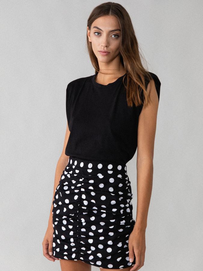 Esta falda corta de popelín en color negro con lunares blancos y con efecto fruncido cuenta con cremallera lateral invisible y tiene un precio rebajado de 9,09 euros. Es de Lefties.