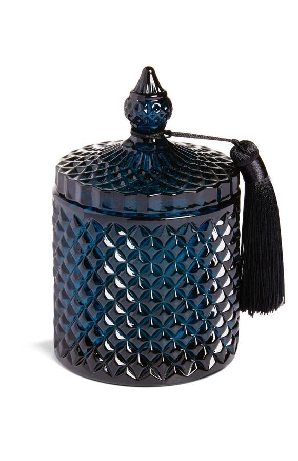 Esta vela en bote de cristal azul oscuro con tapa y borla tiene un precio de 7 euros.