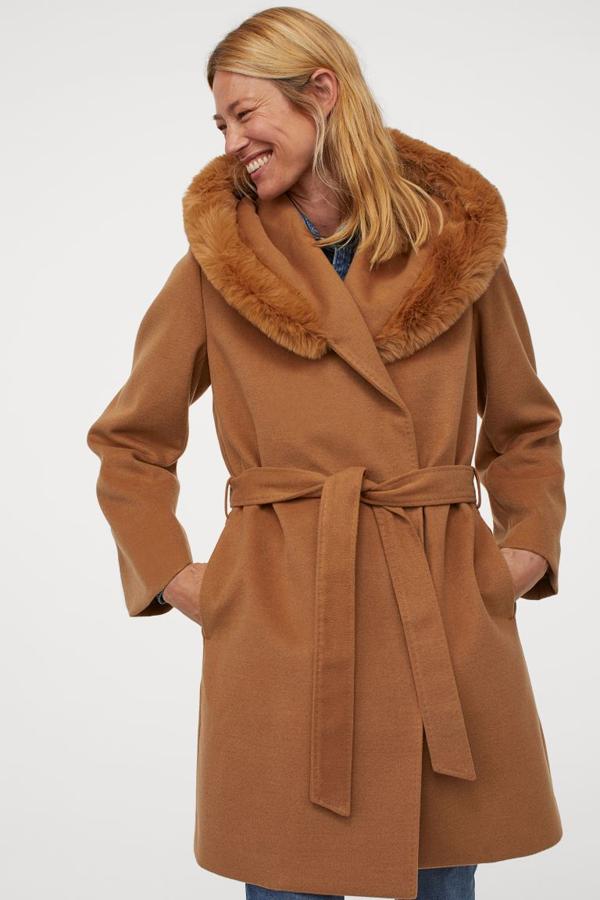 Este abrigo corto de H&M en beige oscuro viene con capucha grande con ribete ancho en pelo sintético, botones de presión ocultos en el frontal y bolsillos en las costuras laterales. Con cinturón extraíble a tono y forro de poliéster reciclado, tiene un precio de 69,99 euros y está disponible entre las tallas XS y XXL.