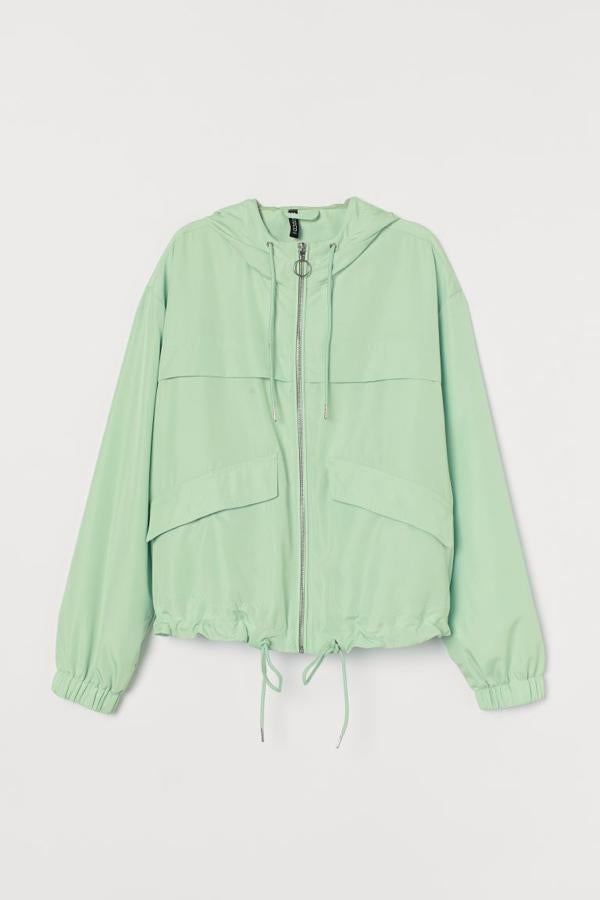 Diseño boxy en tela con cuello elevado, capucha forrada con cordón de ajuste y cierre de cremallera frontal para esta chaqueta de H&M en verde pastel que tiene dos bolsillos delanteros con solapa y elástico revestido en los puños. Podemos encontrarla únicamente en las tallas M y L por 29,99 euros.