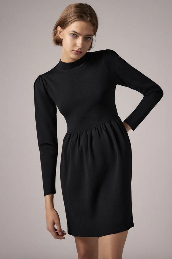 Este vestido negro de punto es de Zara y viene con cuello subido, mangas largas con hombro marcado y bajo acabado en evasé. Podemos encontrarlo en las tallas S, M y L por 29,95 euros.