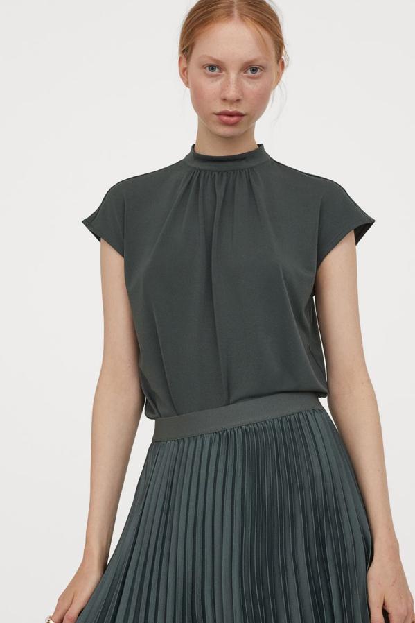 Este top de H&M en punto fluido con mangas japonesas viene con cuello elevado de doble capa con fruncidos frontales y cierre de lágrima con botón en la nuca. Podemos encontrarlo en color burdeos, negro, blanco y caqui por 9,99 euros entre las tallas XS y XXL.