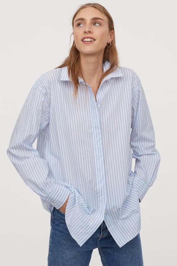 En blanco y azul pastel, esta camisa oversize de H&M en tejido de algodón con cuello clásico, botones frontales ocultos por tapeta y diseño de hombros caídos, tiene el bajo redondeado asimétrico. Cuesta 19,99 euros y está disponible entre las tallas XS y L y en la XXL.