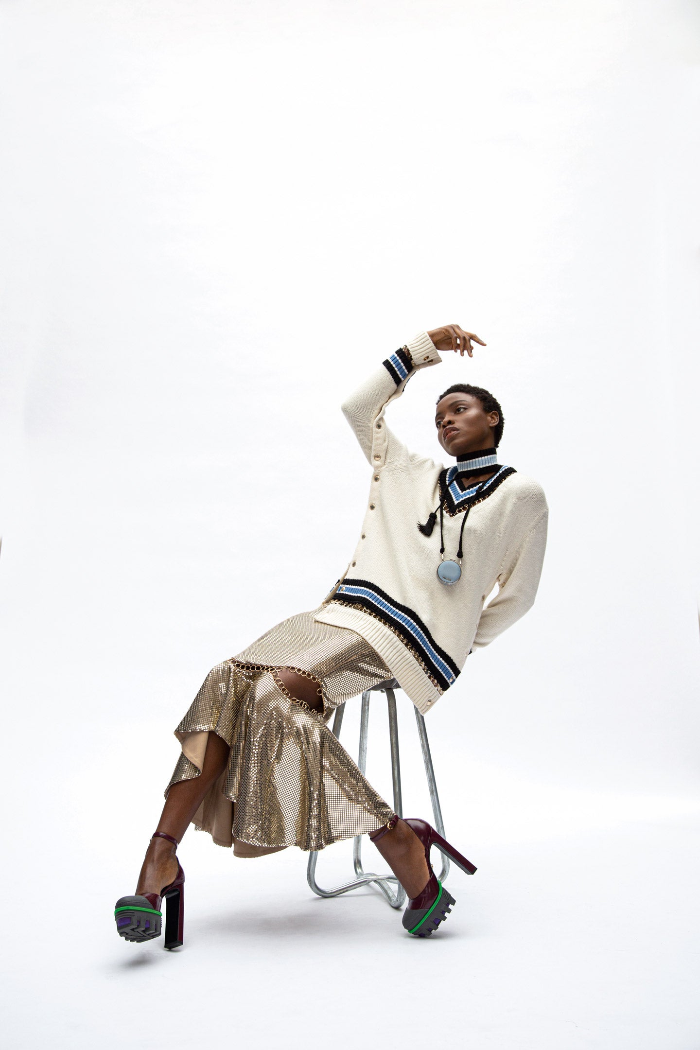 Jersey de punto con gargantilla y falda de malla metálica, ambos de Burberry. Zapatos de Versace y minibolso colgante de nylon, de Prada.