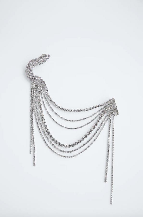 Con flecos y aplicación de joyas de diferentes tamaños, este broche en plata de Zara tiene un precio de 15,95 euros.