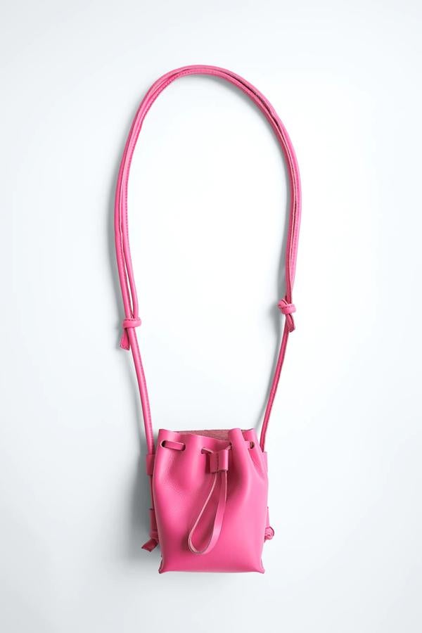 Disponible en fucsia o en negro, este bolso formato mini saca cuenta con asa de hombro tubular con detalle de nudos y cierre mediante fruncido. Es de Zara y tiene un precio de 29,95 euros.