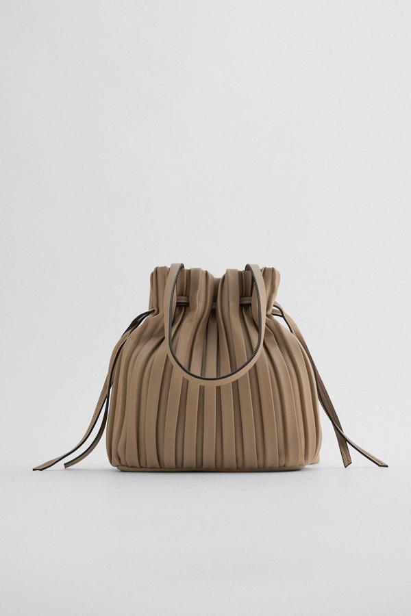 En tono gris visón, este bolso formato mini saca con cuerpo plisado con detalles de fruncido en la parte superior cuenta con asas de hombro y cierre mediante imán. Es de Zara y tiene un precio de 19,95 euros.