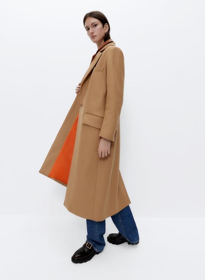 Este abrigo en color camel con cuello clásico y bolsillos laterales de solapa confeccionado en mezcla de lana esconde en el forro su tono más vistoso, el naranja. Cuesta 229 euros y está disponible en las tallas S, M y L.