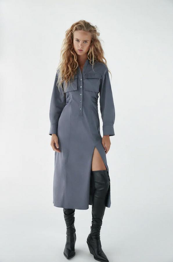 Con cierre de botones a tono hasta la cintura, este vestido camisero de Zara en color gris viene con cuello solapa y manga por debajo del codo acabada en puño con pliegues. Tiene bolsillos de plastrón con solapa en la pechera, detalle de frunces en la cintura y abertura lateral. Cuesta 39,95 euros y está disponible entre las tallas XS y XXL.