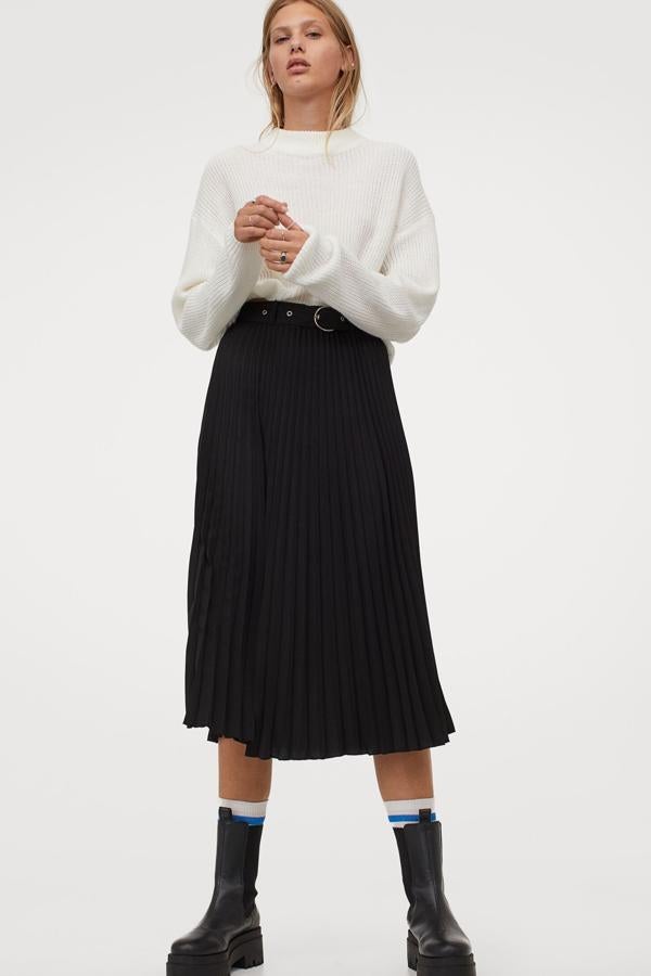 Esta vaporosa falda plisada de color negro y con ligero vuelo cuenta con un cinturón con hebilla de metal y tiene un precio de 24,99 euros. Es de H&M.
