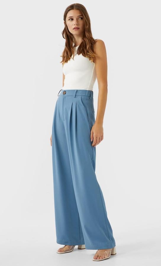 Este pantalón de tiro alto y pernera ancha en color azul cuenta con pinzas en la parte delantera y cierre frontal con cremallera y botón. Es de Stradivarius y tiene un precio de 19,99 euros.