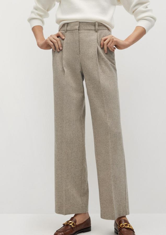 En tejido jaspeado de color beige, este pantalón de pinzas con diseño recto y tiro alto cuenta con trabillas en la cintura y cierre oculto de botón, gancho y cremallera. Es de Mango y tiene un precio de 49,99 euros.