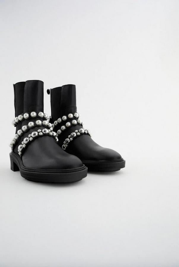 Estos botines con detalles de tiras con perlas son de Zara y viene con corte de piel con elásticos en los laterales y tirador trasero. En color negro, cuestan 79,95 euros y están disponibles entre los números 35 y 42.
