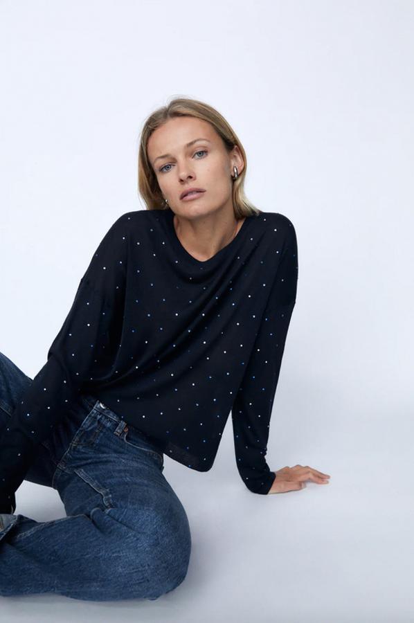 De cuello redondo y manga larga, este jersey en azul marino de Zara que también podemos encontrar en color gris viene con aplicación de brillos combinados a contraste. Solo queda en las tallas S y M y cuesta 19,95 euros.