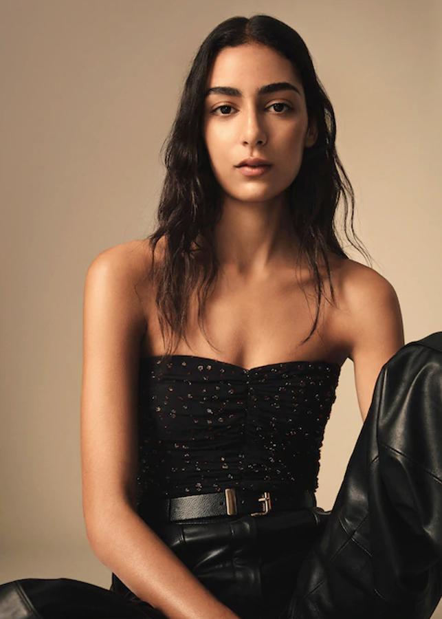 De venta exclusiva en la web de Mango, este top con textura y diseño crop viene con escote drapeado, tirantes finos extraíbles y cierre de cremallera en la espalda. En negro con acabado brillante, podemos encontrarlo entre las tallas XS y L por 29,99 euros.