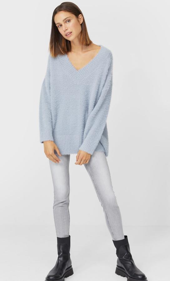 Este jersey largo con cuello de pico y tejido suave de color gris claro está disponible en otros colores y tiene un precio de 25,99 euros.