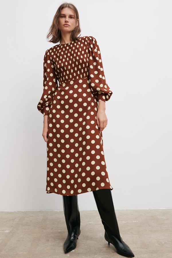 En color burdeos con lunares en crudo, este vestido midi con cuello redondo y manga larga cuenta con detalle de elástico tipo nido de abeja en la parte frontal y bajo acabado en evasé. Es de Zara y tiene un precio de 39,95 euros.