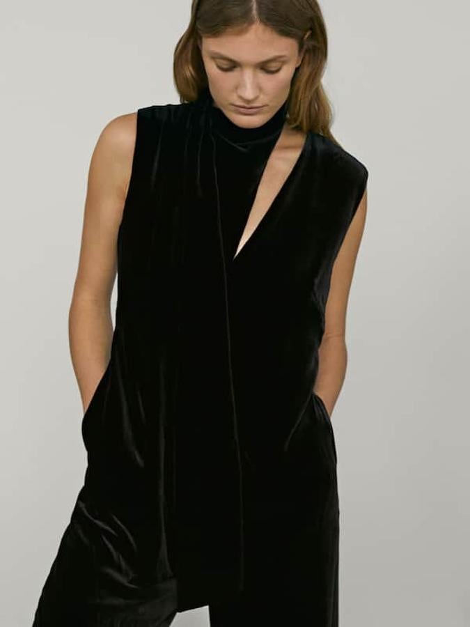 Confeccionado en terciopelo, este mono negro de corte recto viene con cuello con lazada estilo fular multiposición, cierre mediante cremallera en la espalda y dos bolsillos laterales. Podemos encontrarlo entre las tallas 34 y 42 por 149 euros.