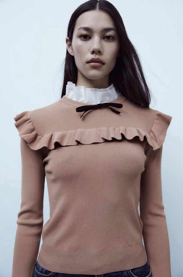 Una de las propuestas más vistosas es este jersey de punto combinado en popelín y lazo de terciopelo en marrón claro es de Zara y viene con cuello subido, puños a contraste y volantes a tono en la pechera y los hombros. Cuesta 25,95 euros y solo queda en la talla XS.