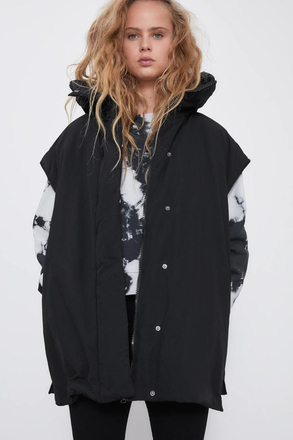 Con tejido repelente al agua de color negro, este chaleco acolchado con cuello subido y capucha cuenta con aberturas laterales con cremalleras y tiene un precio de 49,95 euros.