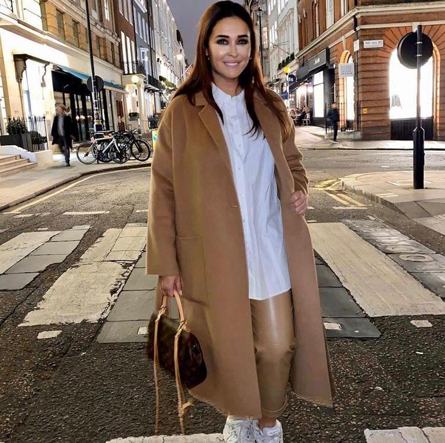 Y no solo el mono, Vicky Martín Berrocal se hizo también con otra prenda de efecto piel:  unos pantalones camel de Zara . Prenda a la que añadió este abrigo largo a juego y camisa y zapatillas blancas.
