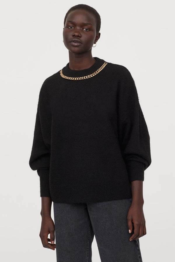 Este jersey negro de H&M confeccionado en punto suave con lana en la trama viene con cuello de canalé adornado con cadena de metal en dorado, mangas amplias y remate de canalé en puños y bajo. Tiene un precio de 24,99 euros y está disponible en las tallas S y M.