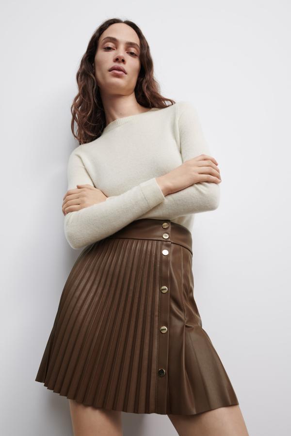 Mini falda plisada efecto cuero de Zara (25,99 euros). En colo marrón y con botones plateados.