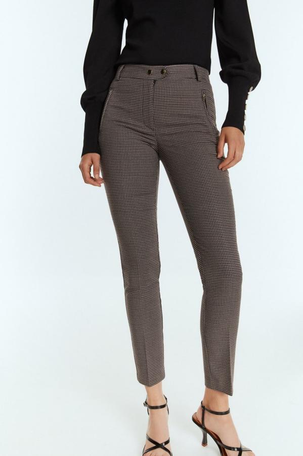 Fondo gris con estampado de cuadro Vichy en azul y burdeos para estos pantalones de diseño ajustado con bajo alto, bolsillos laterales con cremalleras y cierre de botones metalizados. Está disponible entre las tallas 36 y 44 y ha pasado de 19,99 euros a 15,95 euros.