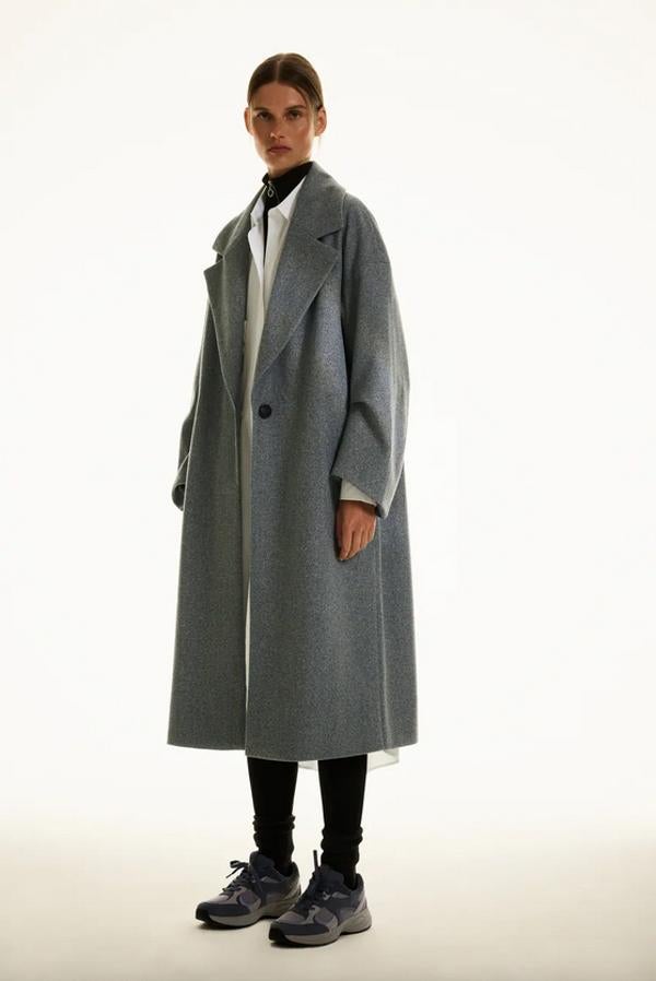 Confeccionado con al menos un 50% de poliéster reciclado, este abrigo largo de Zara en gris oscuro viene con cuello y solapa con muesca, manga larga abullonada con pliegues y bajo acabado con abertura en la espalda. Cuesta 49,95 euros y está disponible entre las tallas XS y XXL y también en gris claro y beige.