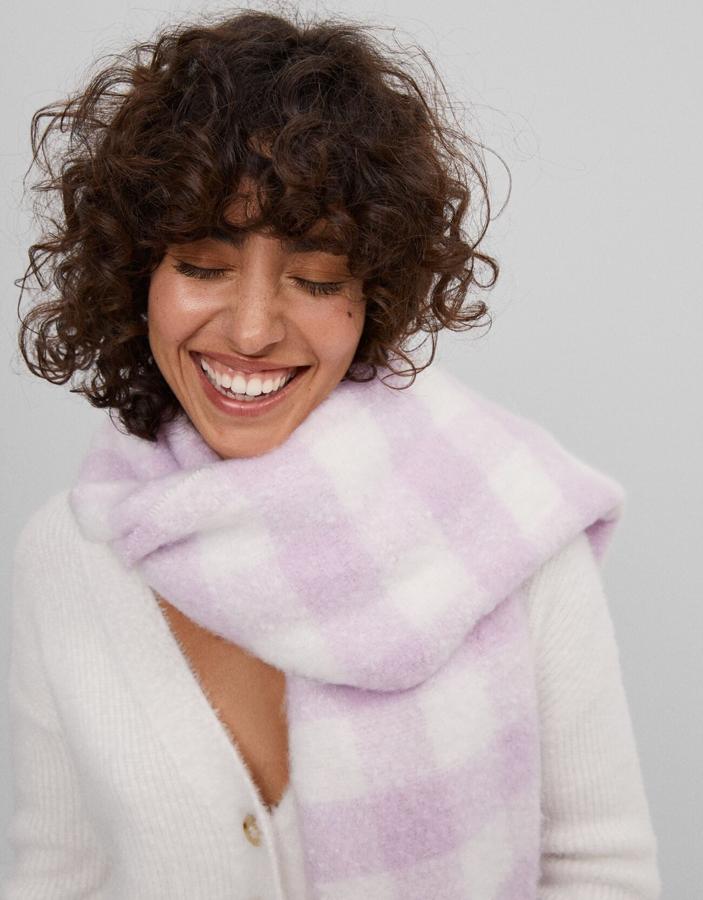 En rosa pastel y blanco, esta bufanda de tacto suave de Bershka con flecos costaba 15,99 euros y ahora tiene un precio de 9,59 euros.