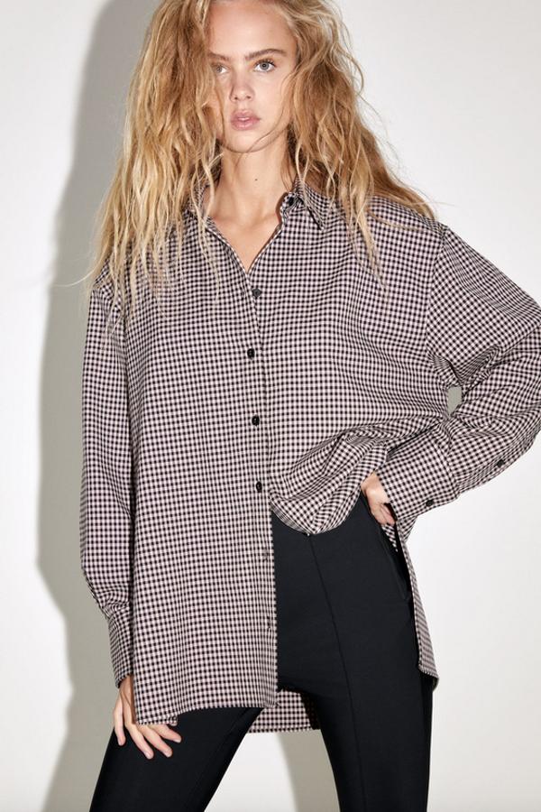 Diseño oversize con cuello solapa y manga larga acabada en puño para esta camisa de Zara en rosa palo y negro con bajo asimétrico con aberturas laterales y cierre frontal con botones. Cuesta 25,95 euros y está disponible entre las tallas XS y XL.