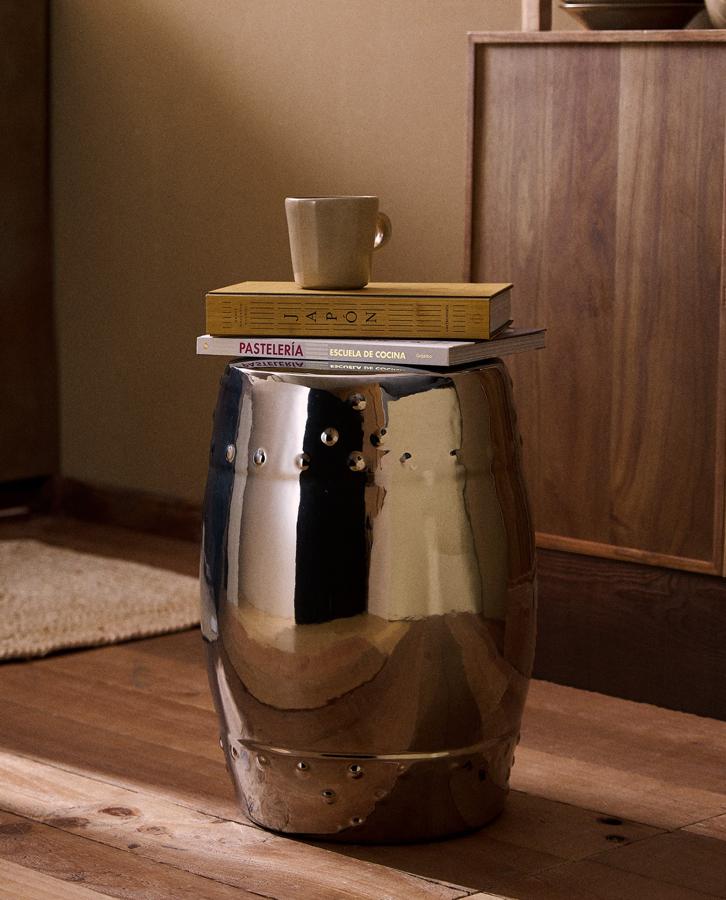 Disponible en plateado o dorado, este taburete hecho en cerámica con efecto metalizado tiene unas medidas de 32x45x32 centímetros y un precio de 99,99 euros.