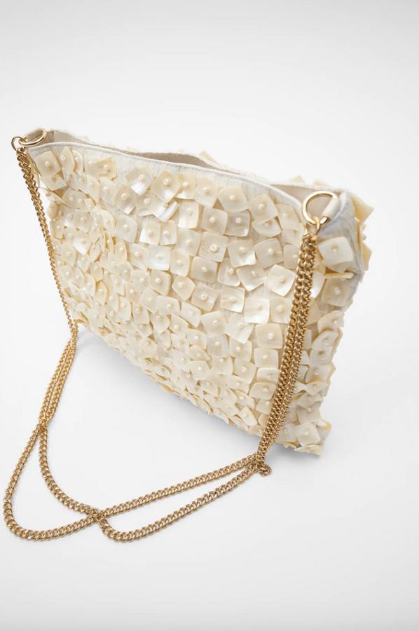 Formato mini para esta saca de Zara en color blanco con el cuerpo en detalle de multipiezas de nácar y abalorios. Con asa de hombro con doble cadena, costaba 29,99 euros y ahora está disponible por 19,99 euros.