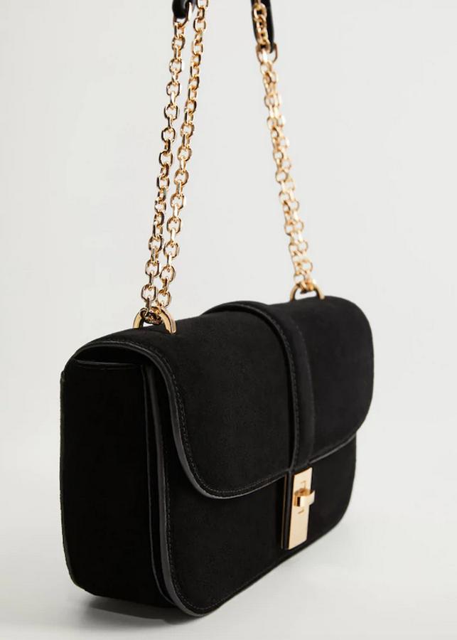 Este bolso negro de piel con asa de hombro en cadena dorada y cierre de clip dorado viene con doble compartimento y solapa frontal. Es de Mango y de 39,99 euros ha pasado a 19,99 euros.