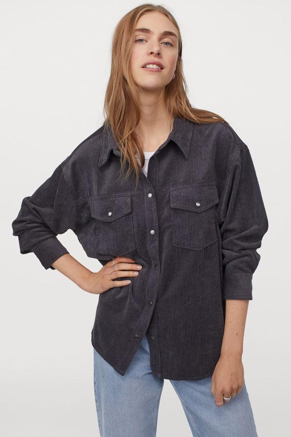 Confeccionada en pana de raya ancha de mezcla de Econyl, con cuello clásico, tapeta de botones delante y bolsillos frontales en la pechera con solapa, esta camisa en gris oscuro de H&M costaba 29,99 euros y ahora está por 14,99 euros y está disponible entre las tallas XS y M.