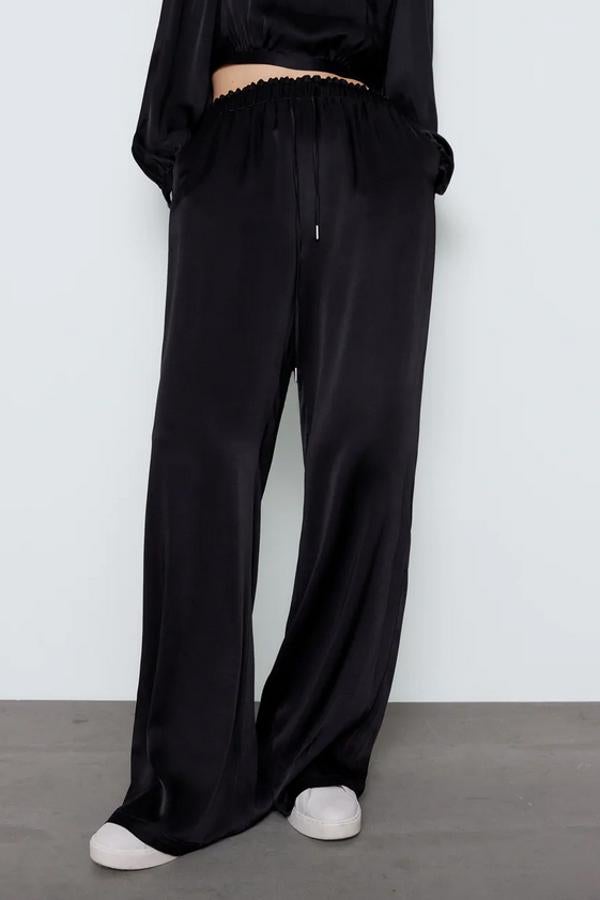 En tejido fluido, con pernera ancha y tiro alto, estos pantalones negros satinados vienen con cintura elástica ajustable con cordones y bolsillos laterales ocultos en la costura. Cuestan 22,95 euros y están disponibles entre las tallas XS y XL.