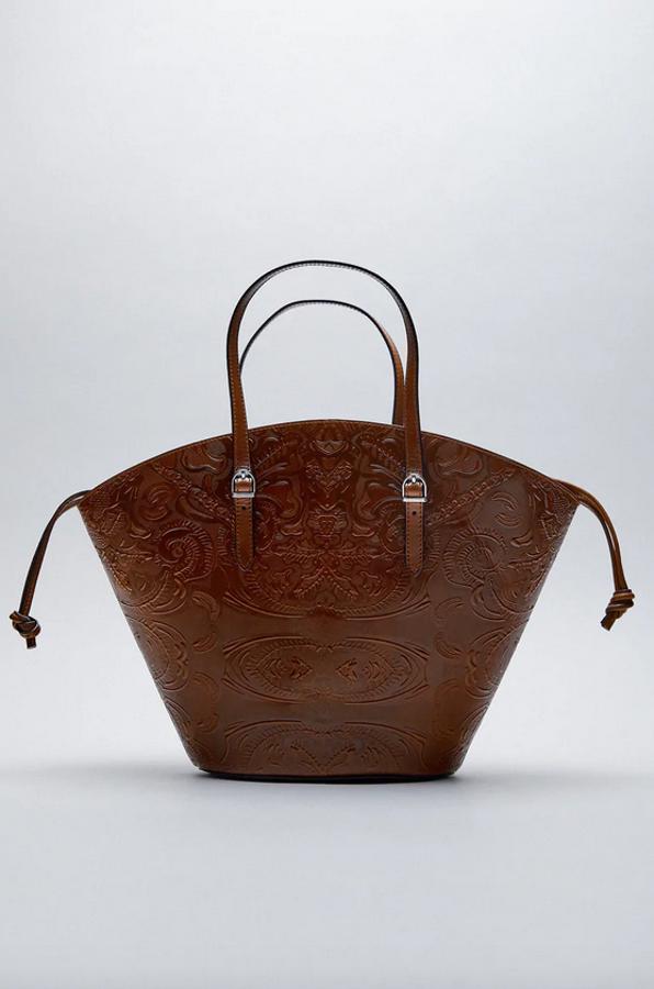 En formato capazo de piel, este bolso con grabados en el cuerpo, asas de mano y de hombro ajustables y cierre de mosquetón metalizado, es de Zara y tiene un precio de 69,95 euros.