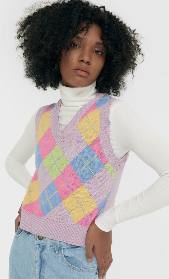 En color lila, con estampado de rombos en rosa, azul, amarillo y verde, este chaleco de cuello de pico acanalado, al igual que las mangas sisa y el bajo, tiene un precio de 19,99 euros y está disponible entre las tallas XS y XL.