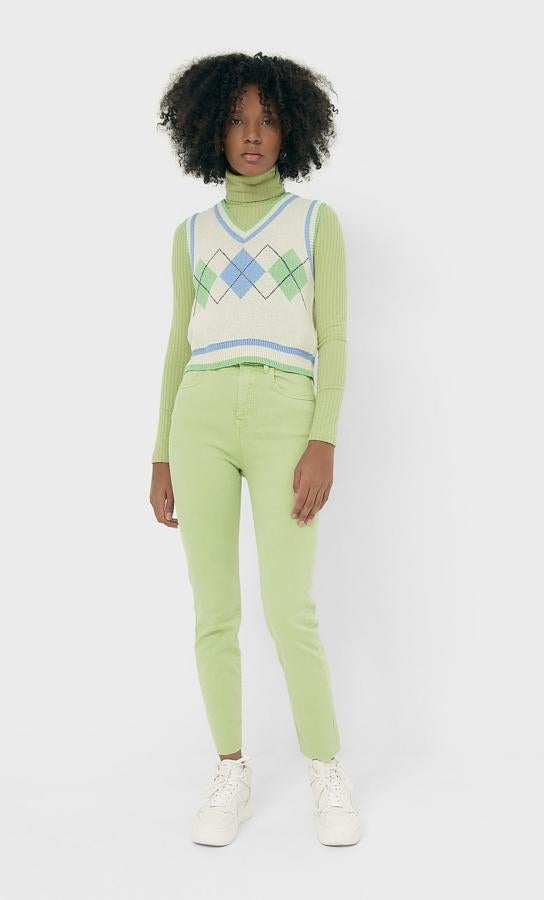 En color crudo, con detalles y estampado en verde y azul, este chaleco de cuello de pico acanalado, al igual que las mangas sisa y el bajo, tiene un precio de 19,99 euros y está disponible entre las tallas XS y XL.