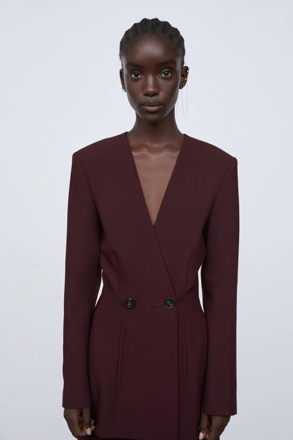 Con escote de pico sin solapa, esta blazer en color burdeos cuenta con hombros marcados y cierre frontal cruzado con botones. Tiene un precio rebajado de 39,99 euros.