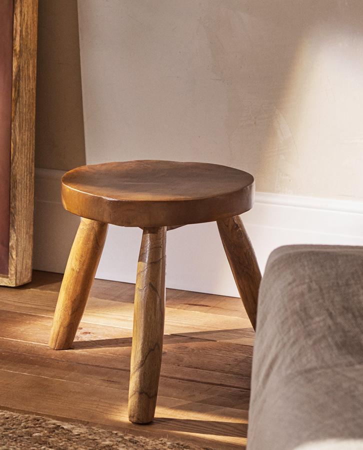 Fabricado en madera de teca, este taburete con tres patas tiene un precio de 49,99 euros y unas medidas de 30x31x30 centímetros.