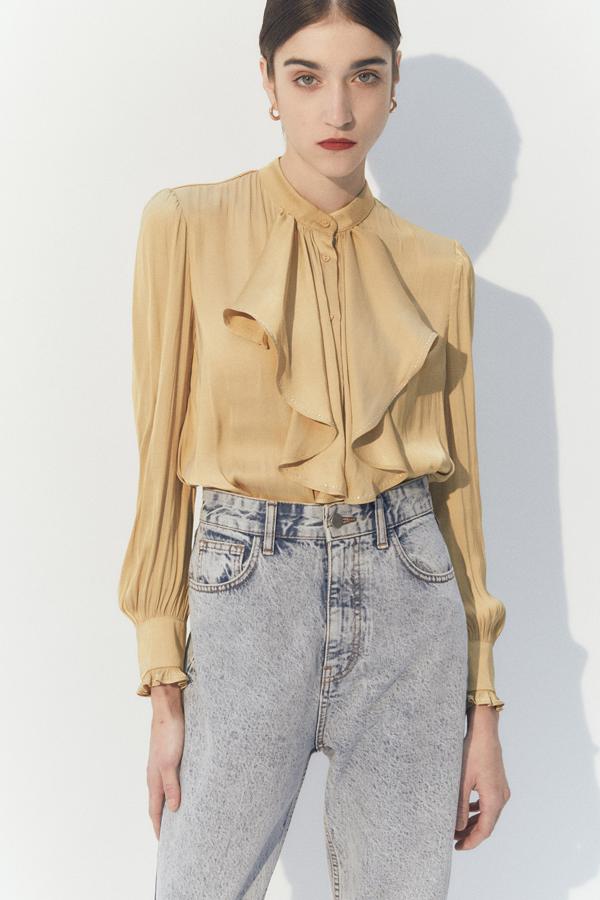 Esta camisa con chorreras en color caqui cuenta con detalles de tachuelas y tiene un pequeño volante en el puño. Su precio rebajado también es de 15,99 euros.