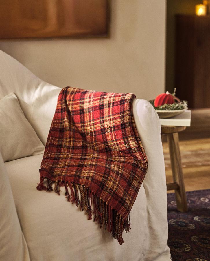 Esta manta con estampado de cuadros está rebajada de 29.99 a 19.99 euros en Zara Home.