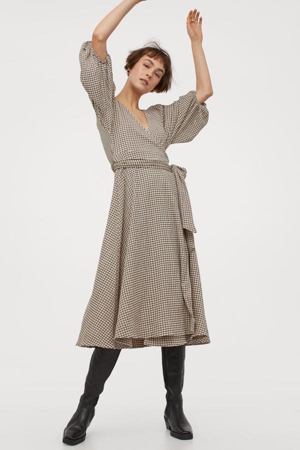 Este vestido en punto de crepé y color beige con estampado de cuadros negros viene con diseño cruzado con escote de pico, mangas globo largas con elástico fino en los puños y lazada ancha en la cintura a tono. Tiene un precio de 49,99 euros y está disponible entre las tallas XS y XXL.