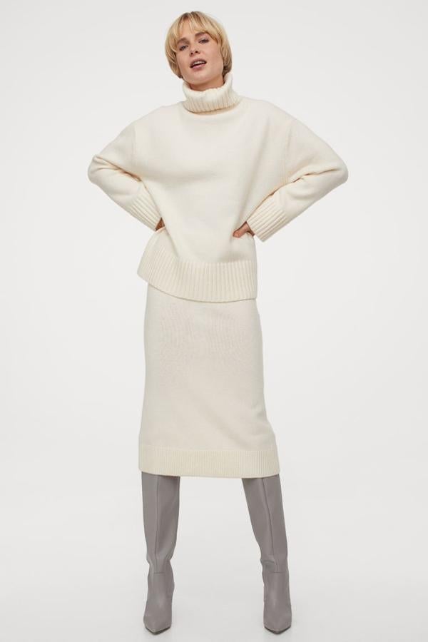 En color crema, esta falda midi de H&M confeccionada en punto suave con lana en la trama es de talle alto y tiene la cintura elástica revestida y el bajo de canalé con abertura posterior. Cuesta 24,99 euros y solo queda en las tallas XS y XXL.