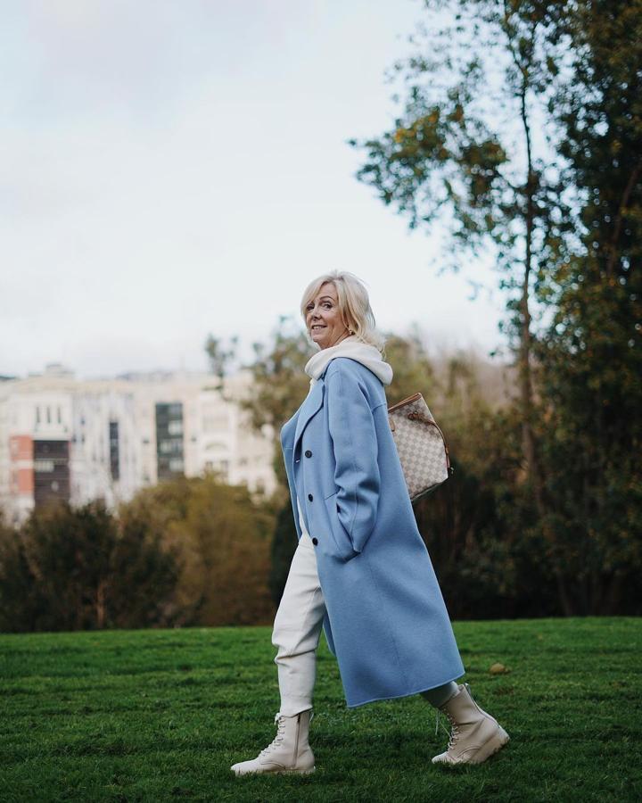 ¿Quién dijo que las prendas de sport no son aptas para las mujeres de 50? Leonor Olabarria demuestra todo lo contraria con este chándal en color beige que combina con botas blancas de Stradivarius y abrigo azul de Zara.