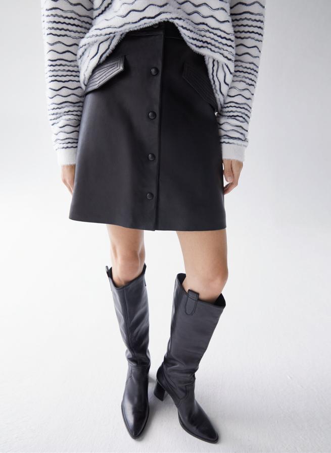 Confeccionada en piel de alta calidad, esta falda mini negra decorada con pespuntes en la cinturilla y las tapetas de los bolsillos laterales viene con botones decorativos en el frontal forrados en piel. Solo queda en la talla L y de 159 euros ha pasado a costar 99,95 euros.